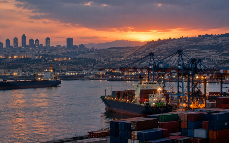 Shipping containers and cargo vessels illustrate international trade restrictions targeting Israeli West Bank settlements amid diplomatic tensions and Israeli retaliation.